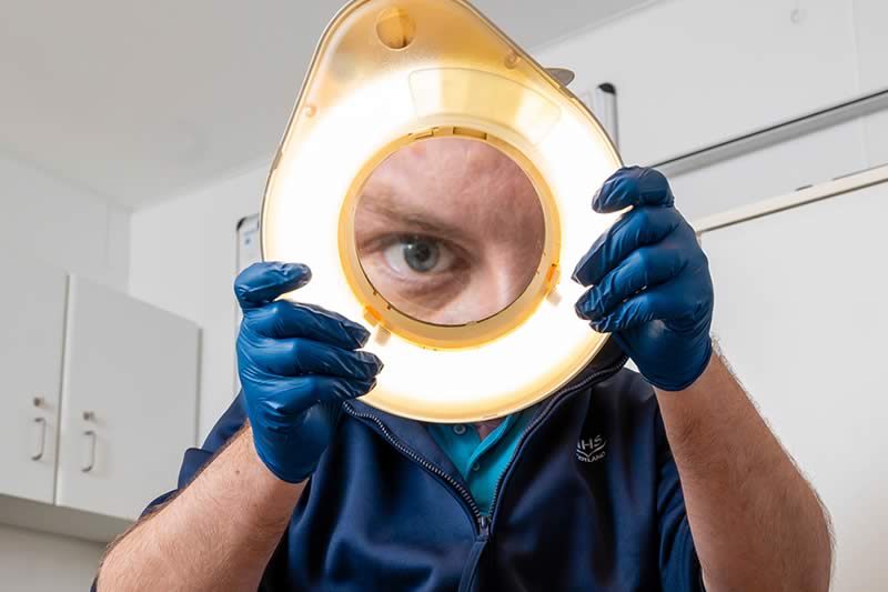 A podiatrist looking through a magnifying ring light