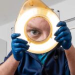 A podiatrist looking through a magnifying ring light
